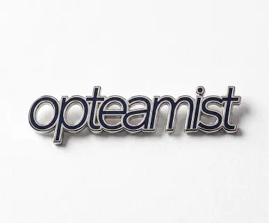 Pin esmaltado con el wordmark de Opteamist en cursiva, sobre fondo blanco